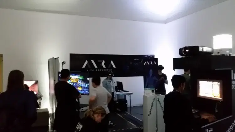 AIRA-VR-Spieler auf der ITFS Expo mit Zuschauern, die das Gameplay auf einem Bildschirm verfolgen.